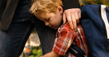 Son clinging to father's leg