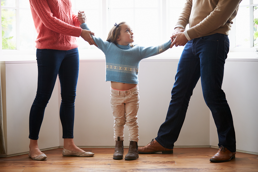 Parents pulling on arms of their child, symbolic of a relationship separation or divorce